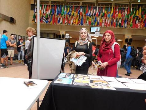 PRISM table set up in the Atrium with students and flags of the world in the background.